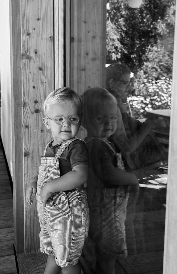 Familienreportagen. Kind betrachtet sich im Fenster