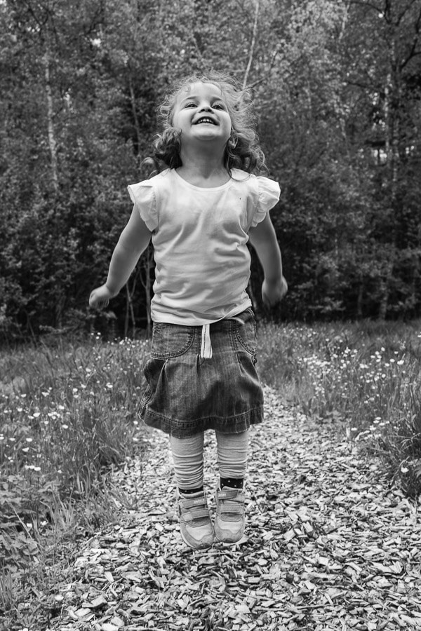 natürliche Familienfotografie. Springendes Kind auf Waldweg.